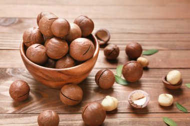 Ahşap arka planda lezzetli macadamia fındıkları olan kase.