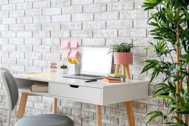 Tuğla duvarın yanında dizüstü bilgisayarı olan modern stil bir iş yeri