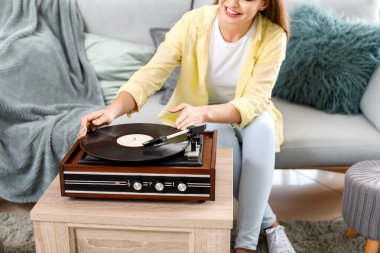 Evde pikapla müzik dinleyen güzel genç bir kadın.