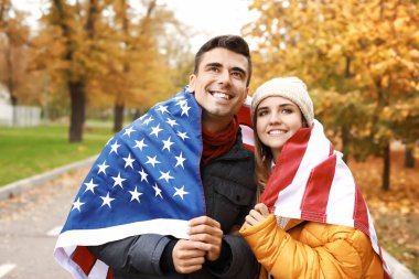 Sonbahar parkında Usa bayrağı taşıyan genç çift