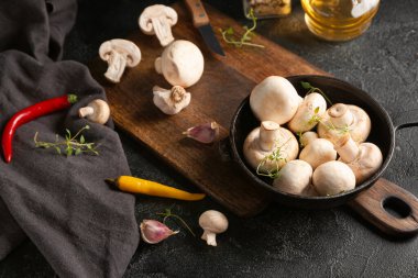 Taze mantarlı tava ve koyu arkaplanda baharatlar.