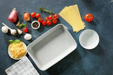 Koyu arkaplanda fırın kabı olan lazanya malzemeleri