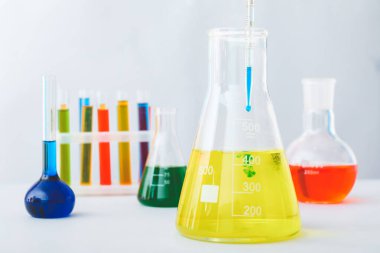 Laboratuvarda renkli numunelerle dolu cam eşyalar.