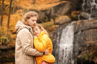 Sonbahar günü şelalenin yanındaki parkta genç bir çift.