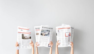 Female hands with newspapers on light background clipart