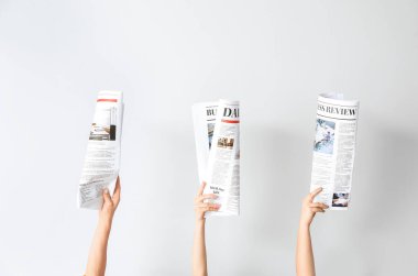 Hafif arka planda gazeteleri olan kadın eller