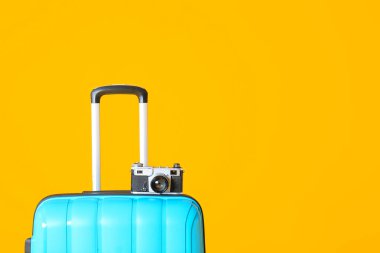 Renkli arka planda bavul ve fotoğraf makinesi var. Seyahat kavramı
