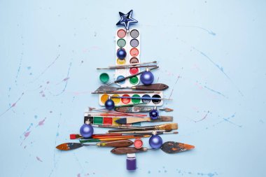 Renk arkaplanındaki boya aletlerinden yapılmış güzel Noel ağacı
