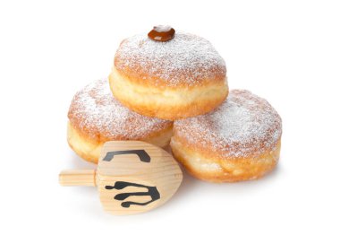 Hanuka için lezzetli çörekler ve beyaz arka planda dreidel.