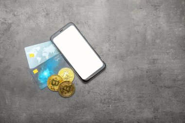 Gri arkaplanda cep telefonu, bitcoin ve kredi kartları