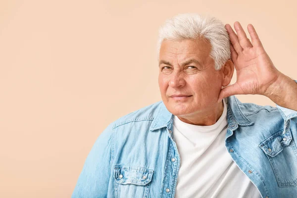 Mature man with hearing problem on light background — Stock Photo, Image