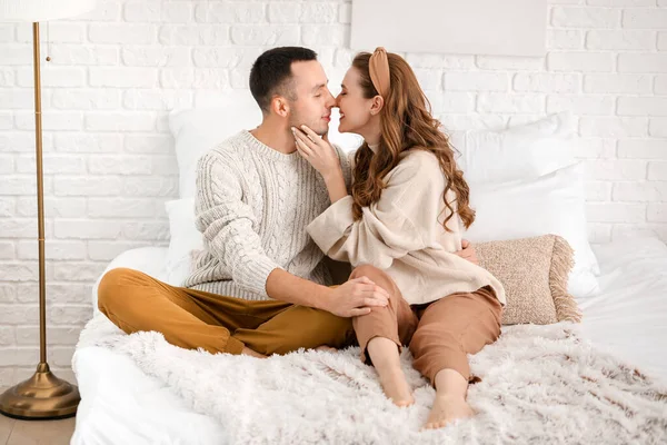 Hermosa pareja joven sentada en la cama en casa —  Fotos de Stock