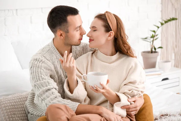 Hermosa pareja joven sentada en la cama en casa — Foto de Stock