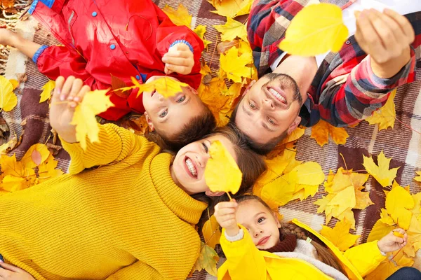 Familia feliz con hojas de otoño acostado en cuadros, vista superior — Foto de Stock