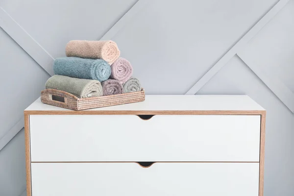 Clean towels on chest of drawers near light wall — Stock Photo, Image