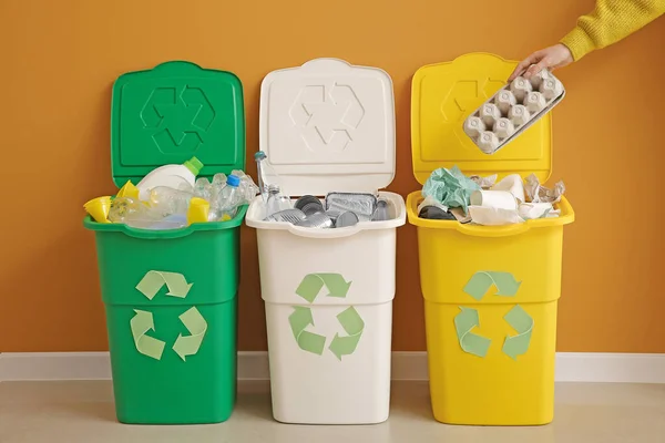 Woman throwing garbage into container. Recycling concept