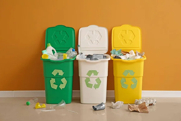 Contenedores con diferentes tipos de basura cerca de la pared de color. Concepto de reciclaje — Foto de Stock