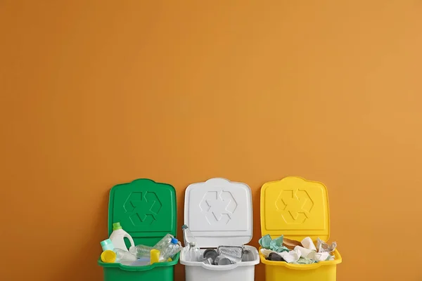 Recipientes com diferentes tipos de lixo perto da parede colorida. Conceito de reciclagem — Fotografia de Stock