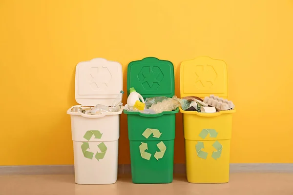 Recipientes com diferentes tipos de lixo perto da parede colorida. Conceito de reciclagem — Fotografia de Stock