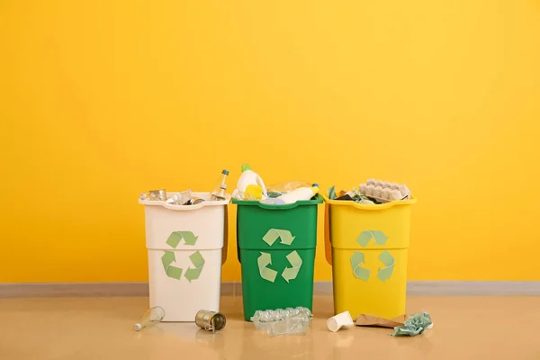 Recipientes com diferentes tipos de lixo perto da parede colorida. Conceito de reciclagem — Fotografia de Stock