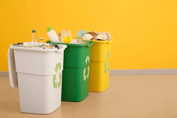 Контейнери з різними типами сміття біля кольорової стіни. Концепція переробки — стокове фото