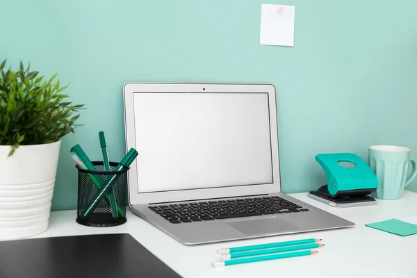 Comfortable workplace with modern laptop near color wall — Stock Photo, Image