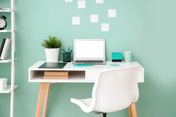 Comfortable workplace with modern laptop near color wall — Stock Photo, Image