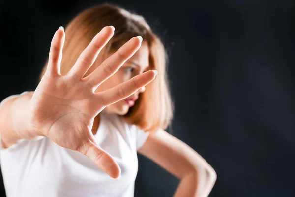 Cute teenage girl showing stop gesture on dark background — Stock Photo, Image