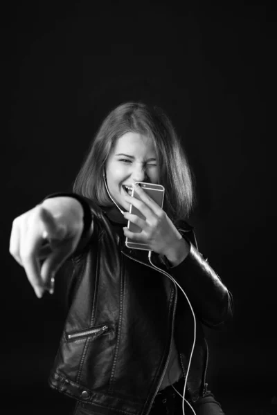 Black and white portrait of happy teenage girl listening to music on dark background — Stock Photo, Image