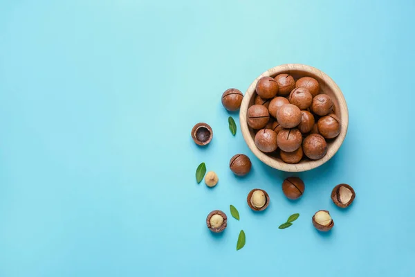 Bowl with tasty macadamia nuts on color background — Stock Photo, Image