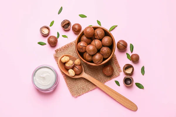 Macadamia nuts with cream on color background — Stock Photo, Image