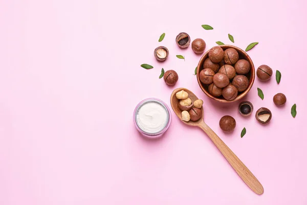 Macadamia nuts with cream on color background — Stock Photo, Image