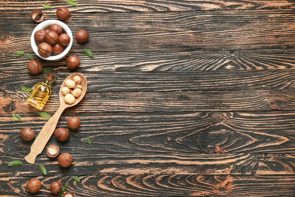 Lekkere macadamia noten met olie op houten ondergrond — Stockfoto