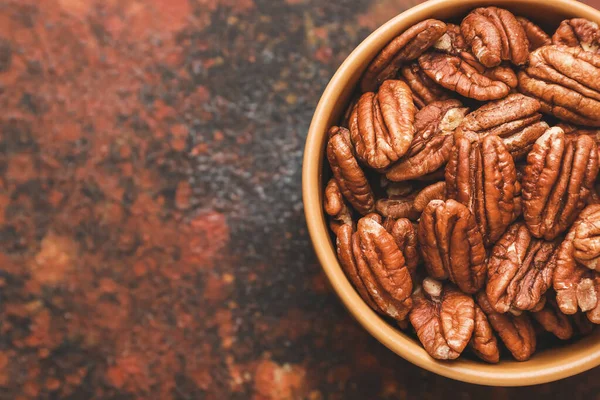 Bowl with tasty pecan nuts on color background — Stock Photo, Image