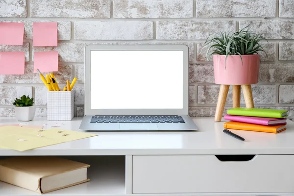 Modern stylish workplace with laptop near brick wall — Stock Photo, Image