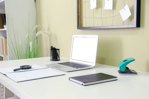 Moderno lugar de trabajo elegante con ordenador portátil cerca de la pared de color — Foto de Stock