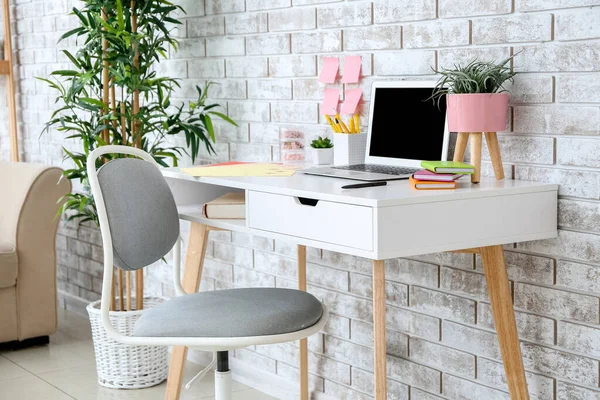 Modern stylish workplace with laptop near brick wall — Stock Photo, Image