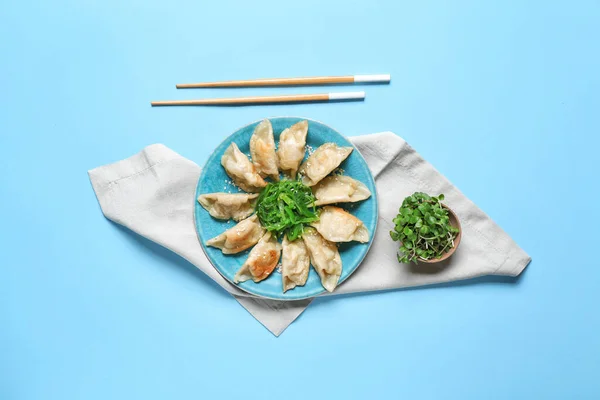 Plate with tasty Japanese gyoza on color background — Stock Photo, Image