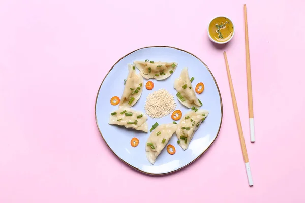 Placa com gyoza japonês saboroso e molho sobre fundo de cor — Fotografia de Stock