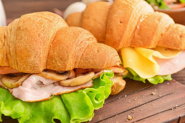 Νόστιμα κρουασάν σάντουιτς σε ξύλινη σανίδα, κοντινό πλάνο — Φωτογραφία Αρχείου