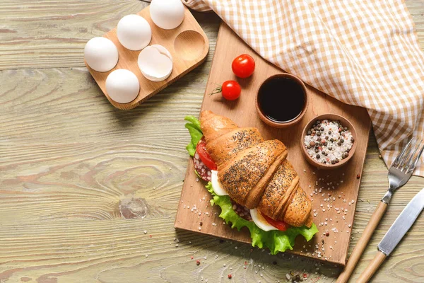 Bord met lekkere croissant sandwich op houten tafel — Stockfoto