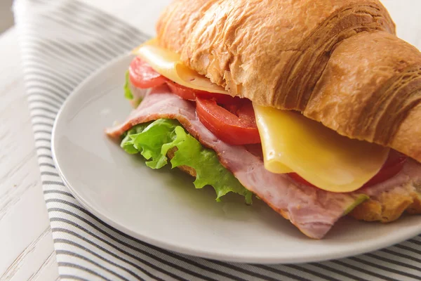 Teller mit leckerem Croissant-Sandwich auf dem Tisch — Stockfoto
