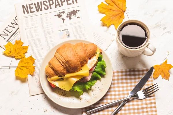 Sabroso sándwich de croissant con taza de café sobre fondo blanco — Foto de Stock