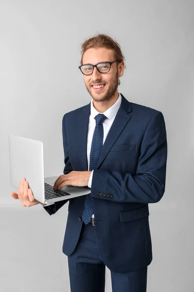 Portrait of businessman with laptop on grey background — Stock Photo, Image