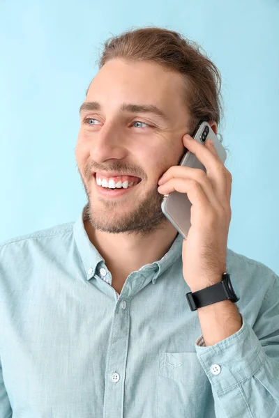 Portrait of happy man talking by mobile phone on color background — Stock Photo, Image