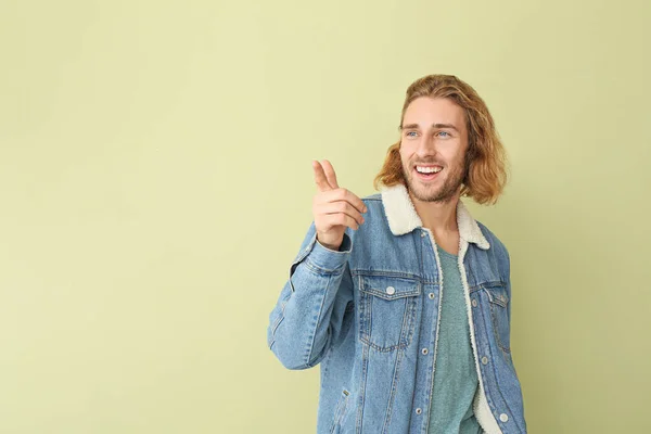Portrait of handsome man pointing at something on color background — Stock Photo, Image