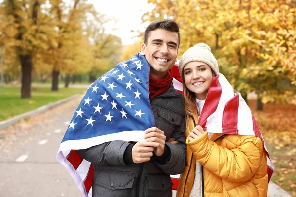 가을 공원에서 미국 국기를 든 젊은 부부 — 스톡 사진