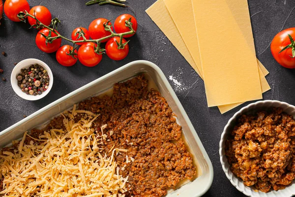 Koken van smakelijke lasagne op donkere achtergrond — Stockfoto