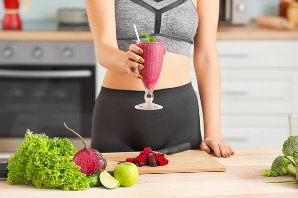 Mujer deportiva con vaso de batido saludable en la cocina — Foto de Stock