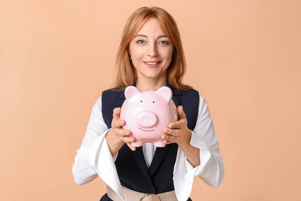 Mulher madura com banco porquinho no fundo de cor — Fotografia de Stock